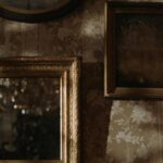 Vintage gold ornate picture frames on a floral patterned wallpaper, featuring an antique mirror and classic decorative wall decor, ideal for vintage home styling.