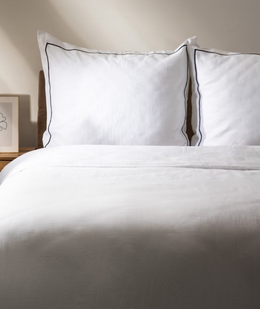 Duvet Set Esperin – Elegant white cotton satin duvet cover set featuring a minimalist design with subtle dark piped edging. Includes one large duvet cover and two matching pillowcases, each showcasing crisp tailoring and premium quality for a luxurious bedroom look. Perfect for stylish home décor, modern bedrooms, and lovers of refined minimalist bedding. Ideal for king or queen size beds, creating a fresh, inviting, and sophisticated ambience.